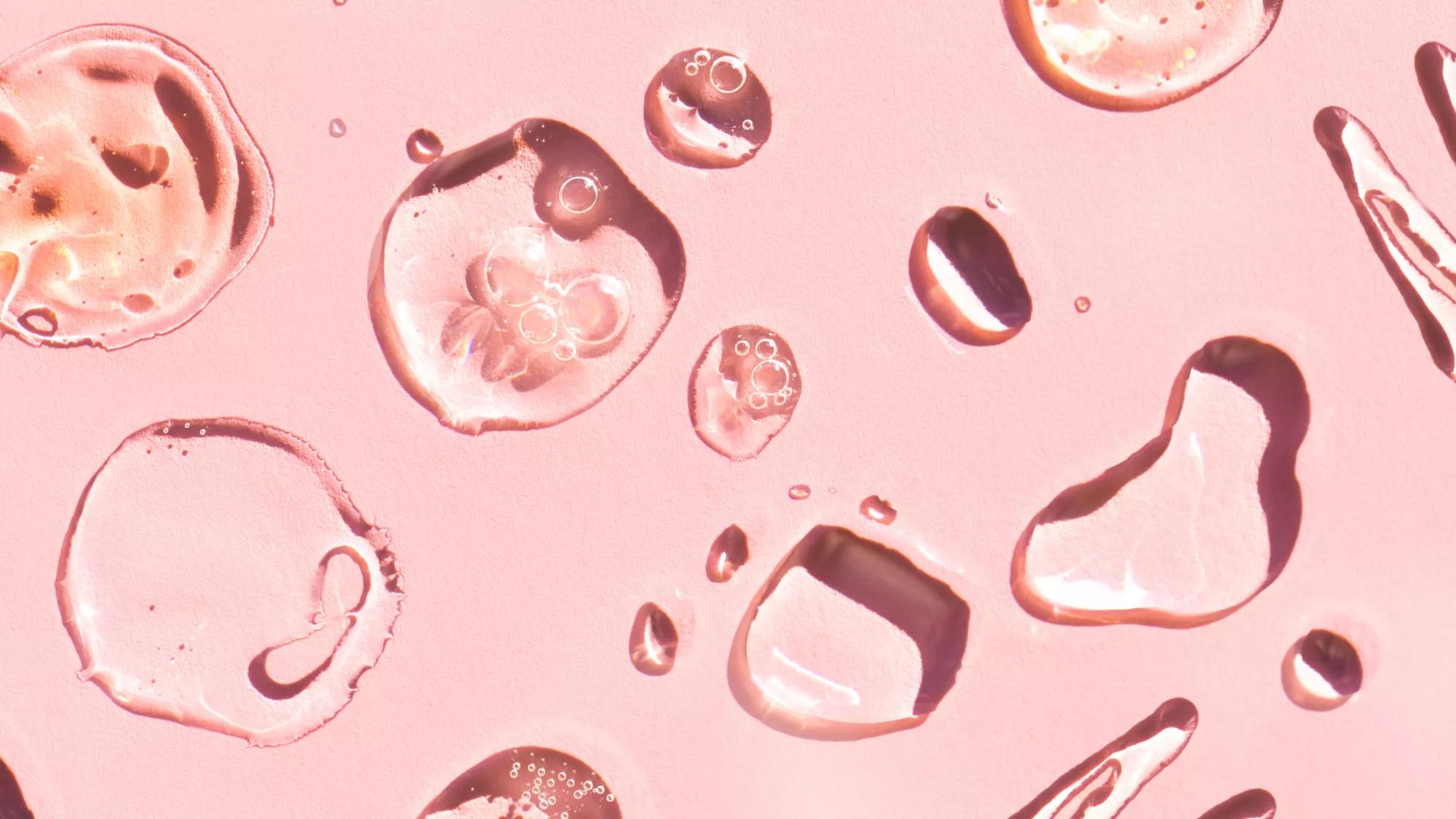 Water droplets resting on a pink background