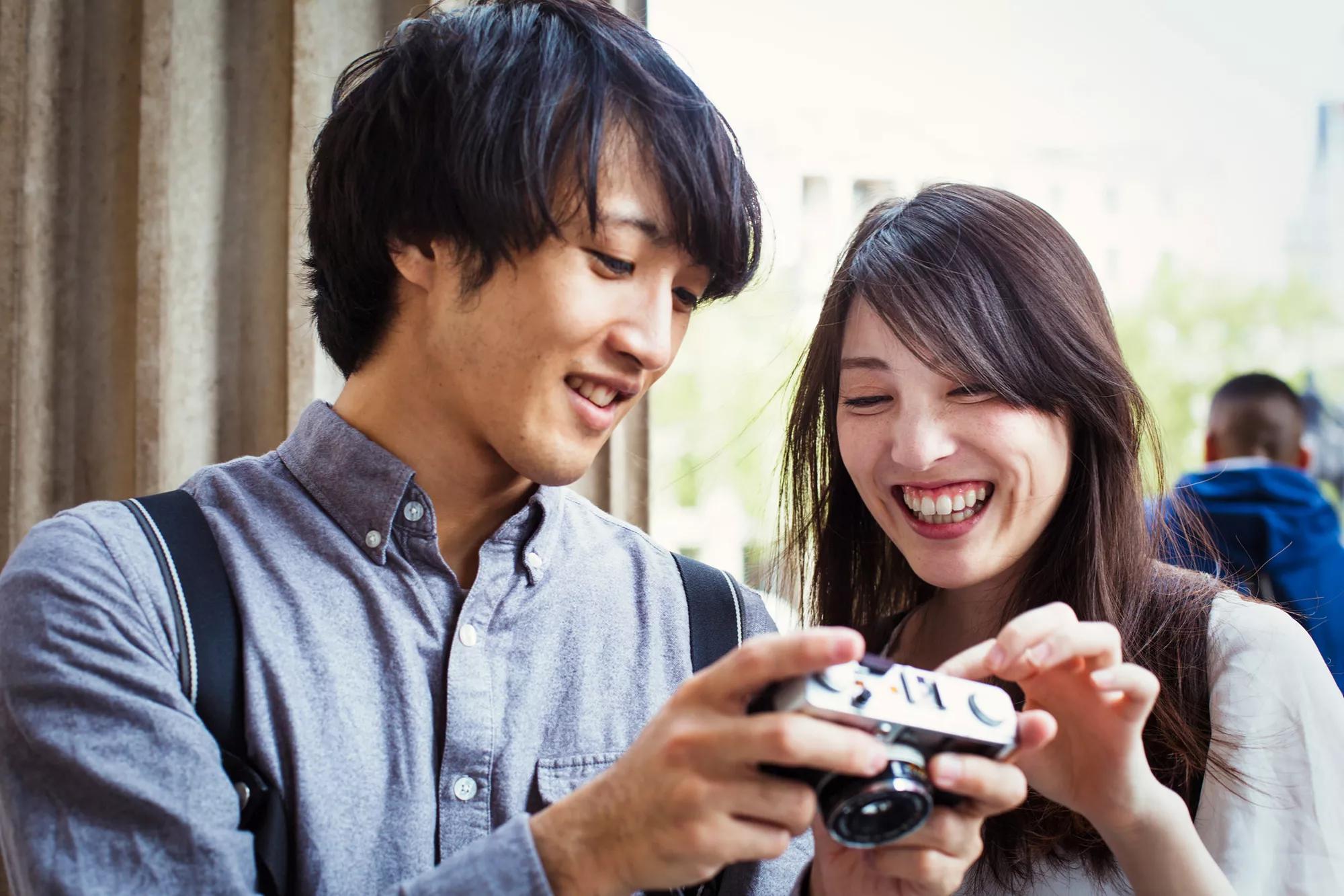 Asian boy and girl smiling while looking at a vintage camera