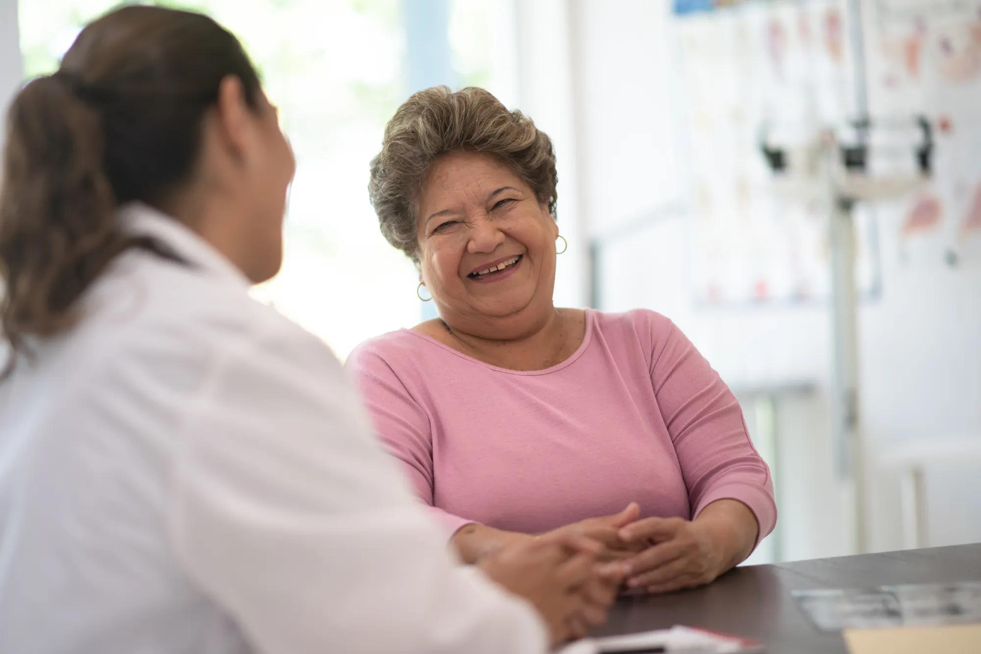 Older woman smiling and consulting with her doctor about her concerns