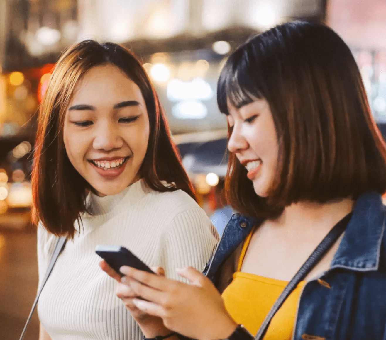 Two young Asian women looking at a cellphone