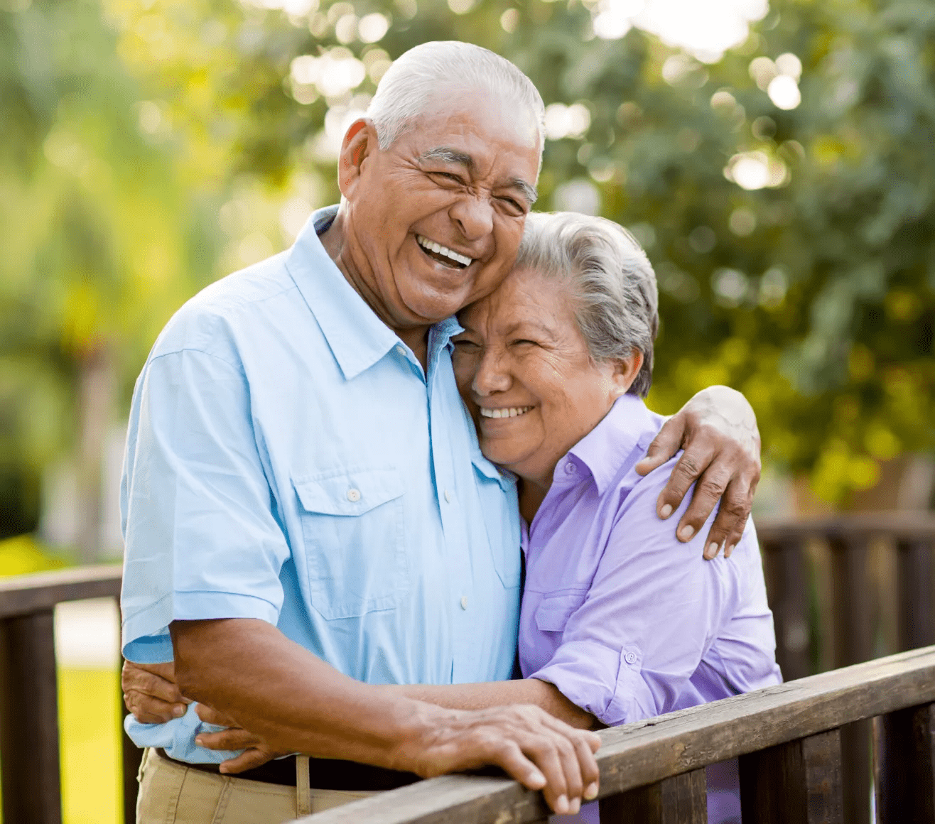 An elderly couple hugging outside