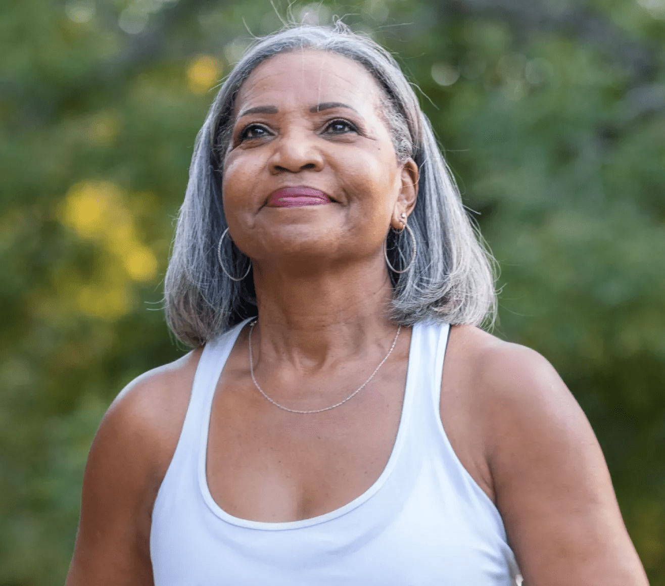 Grey haired Black lady wearing a white tank top