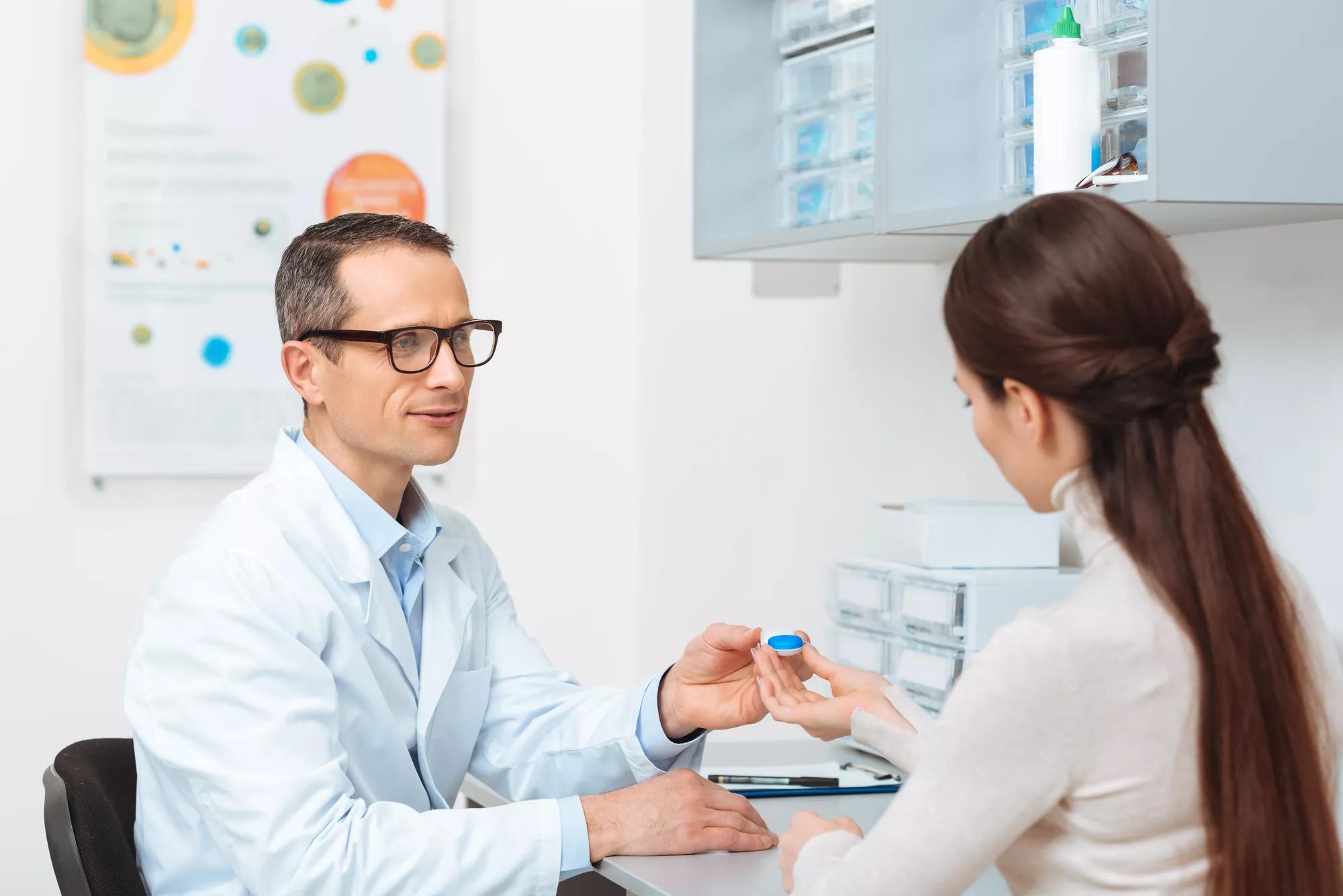 Male Doctor and Female Patient exchanging a contact lens in a doctor's office