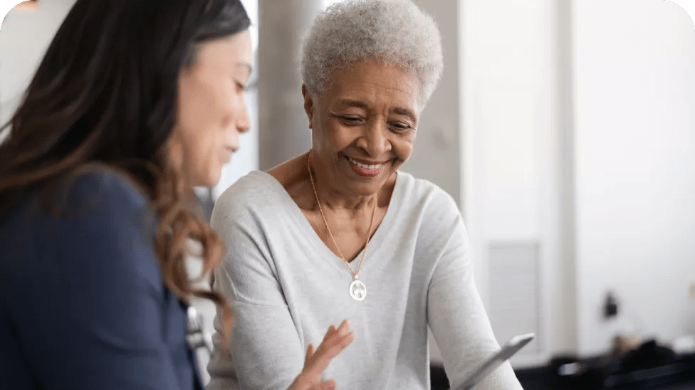 Duas mulheres sorrindo olhando para a tela de um smartphone 