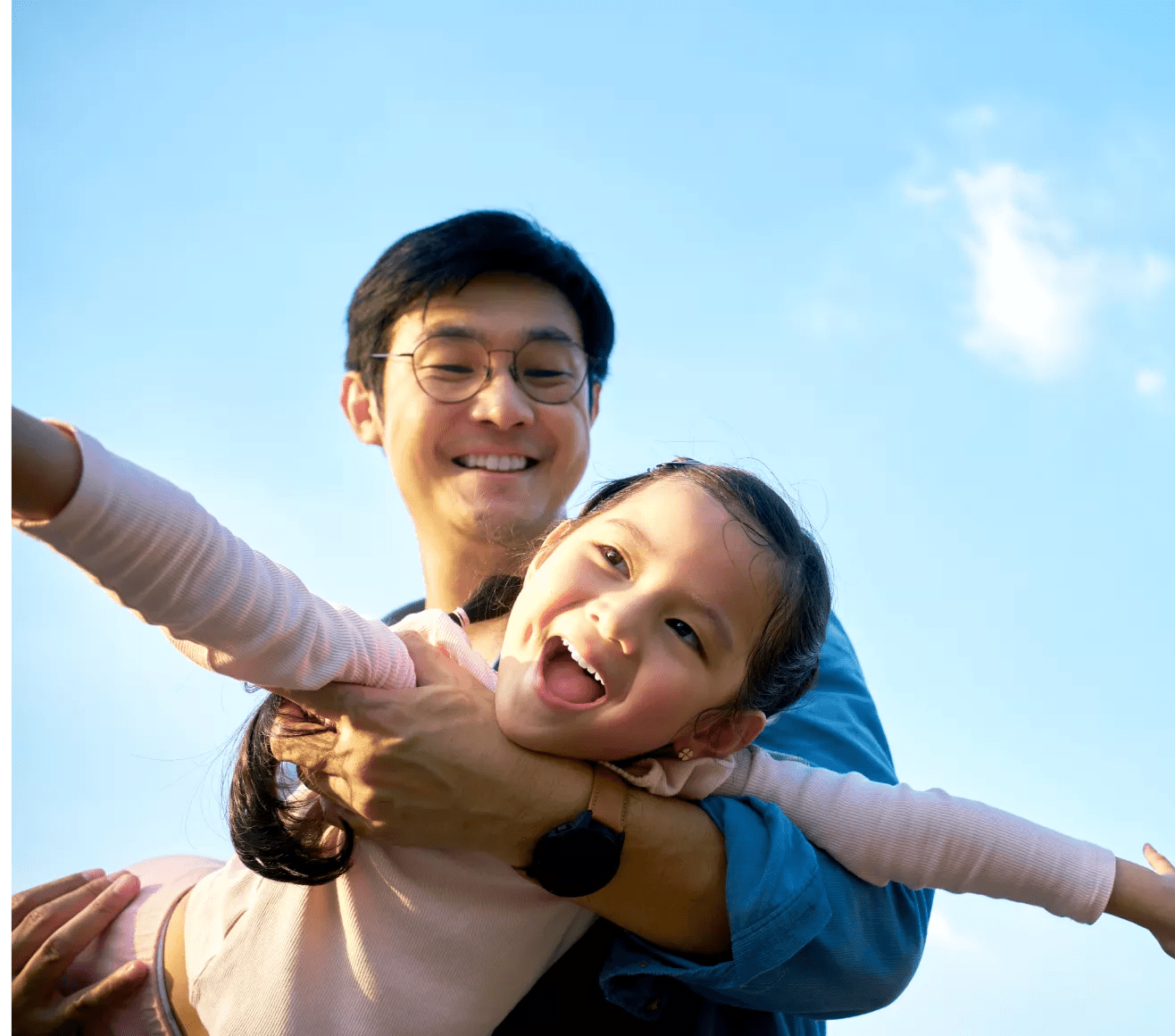 Asian father holding daughter with her arms spread out