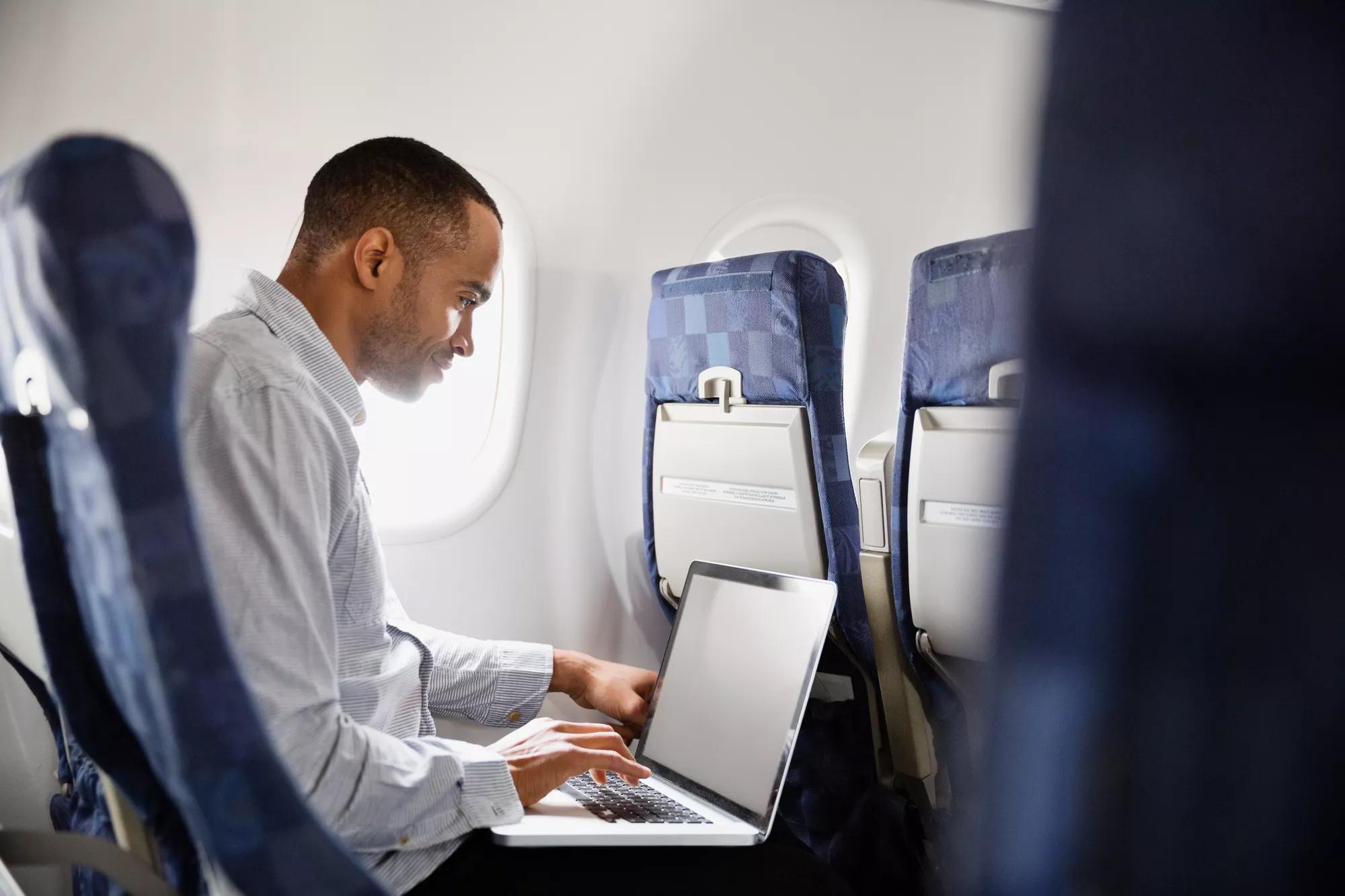 a man working on his laptop on an airplane