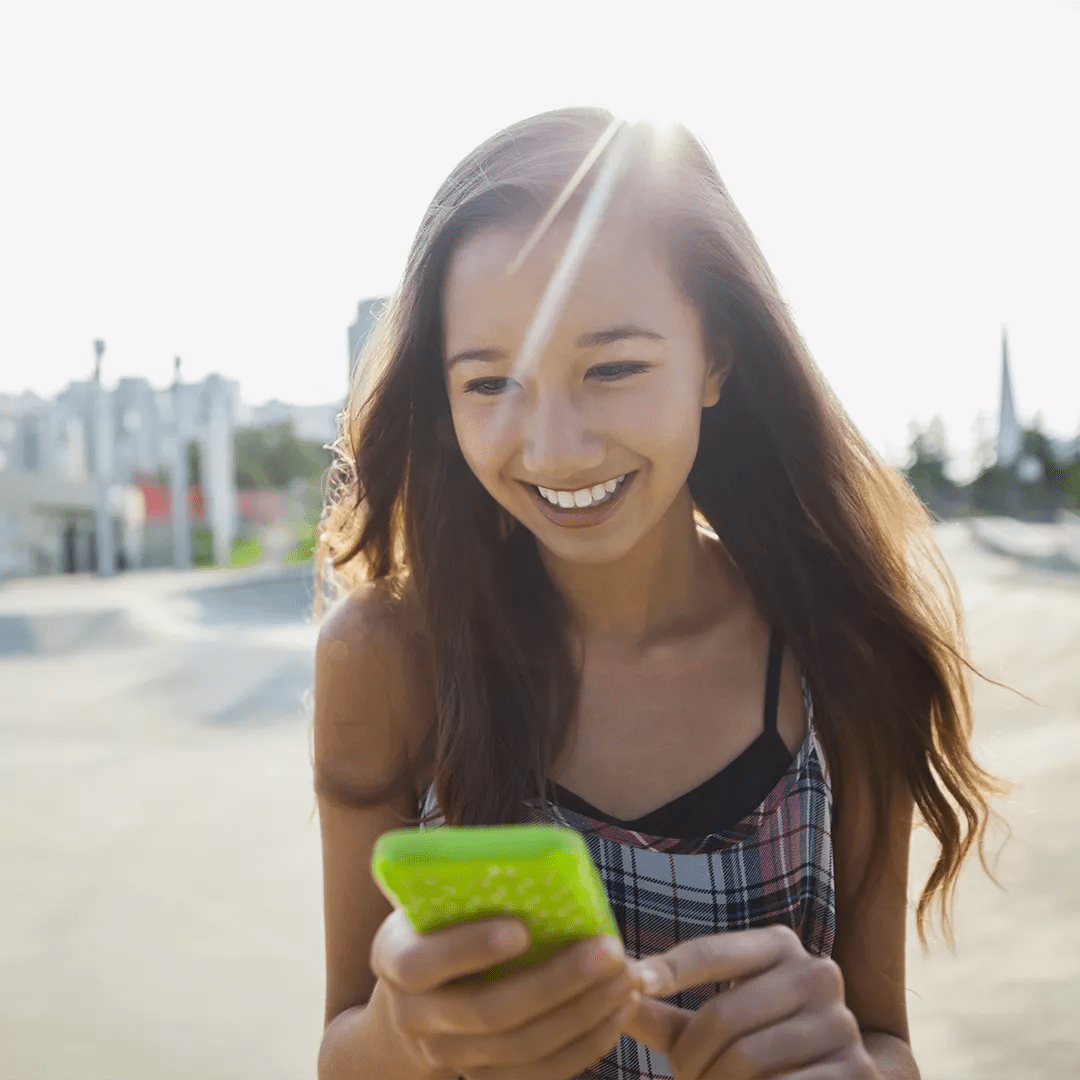 A young girl gazing intently at green cell phone