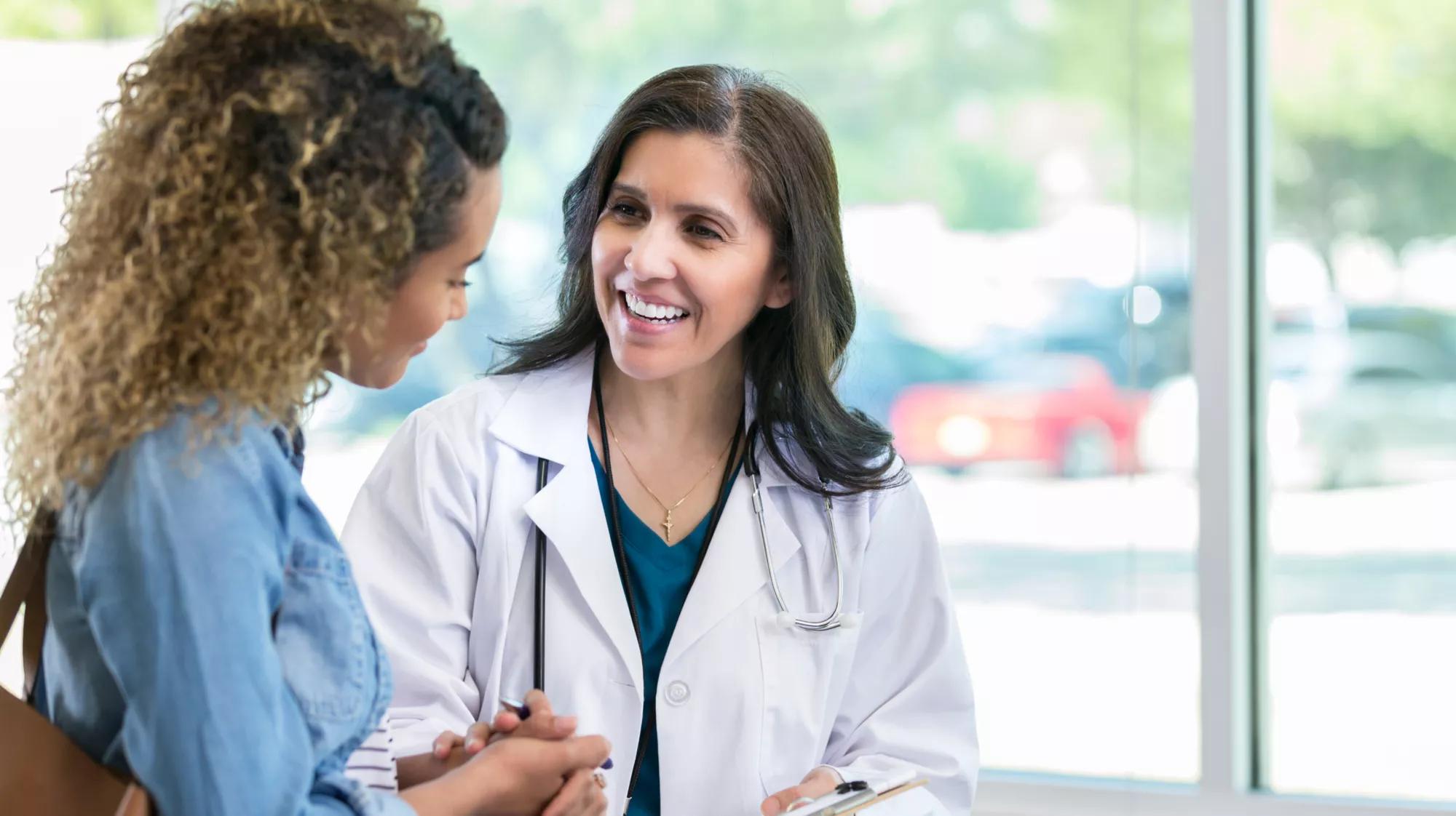 Image of a smiling doctor speaking to a woman with wavy hair