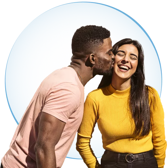 A young black man kissing a woman on the cheek as she smiles.