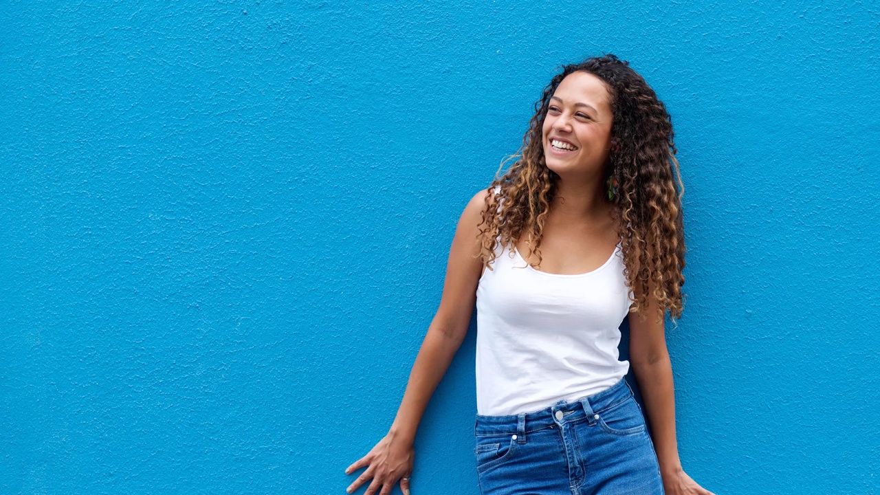 Ragazza con i capelli ricci sorridente su sfondo azzurro