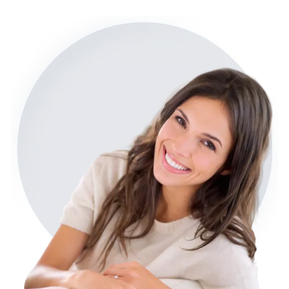 A Smiling young woman sitting in the living room wearing a white t-shirt.