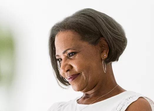 Old black woman with short hair smiles looking off to left.