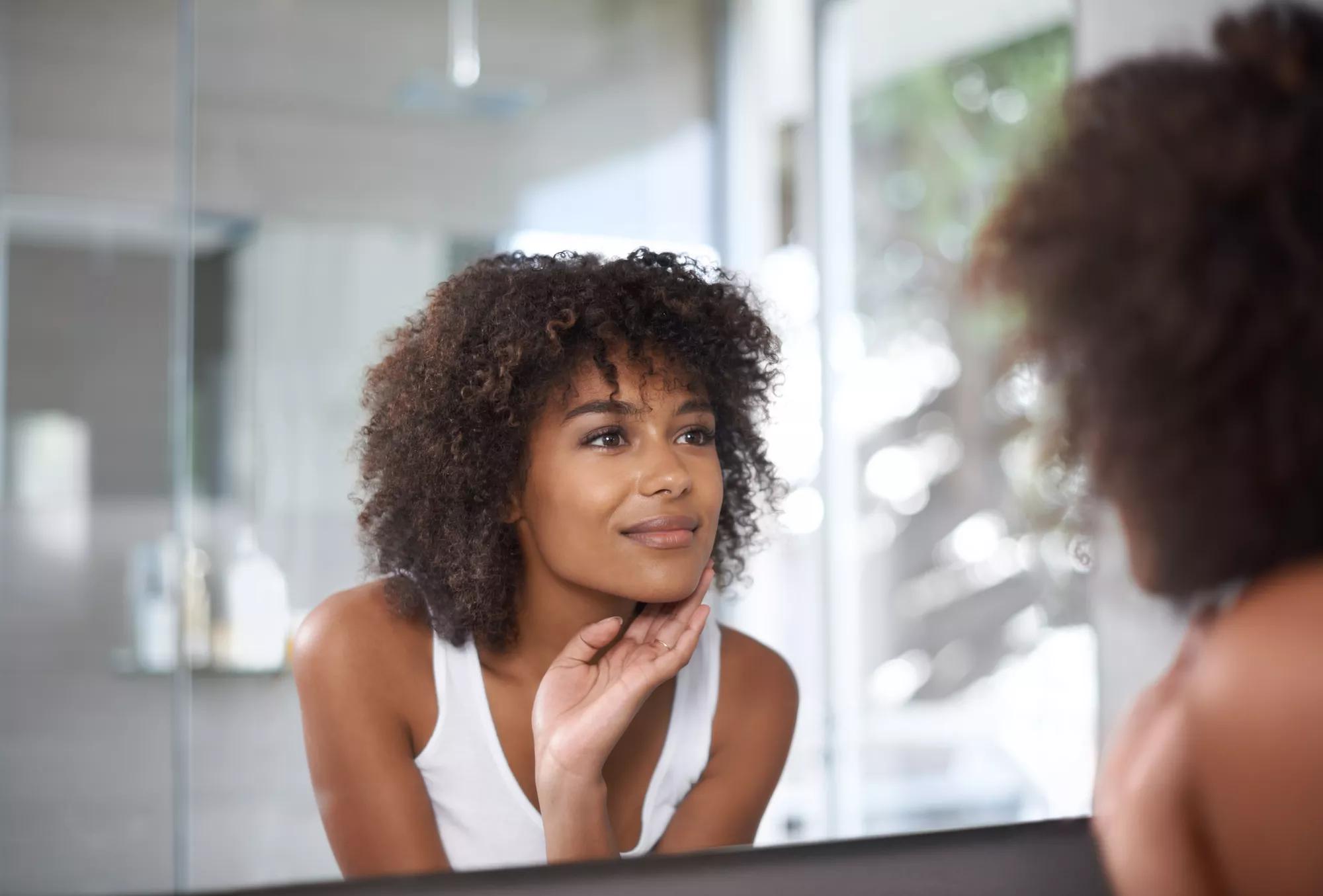 Une jeune femme noire qui sourit dans le miroir