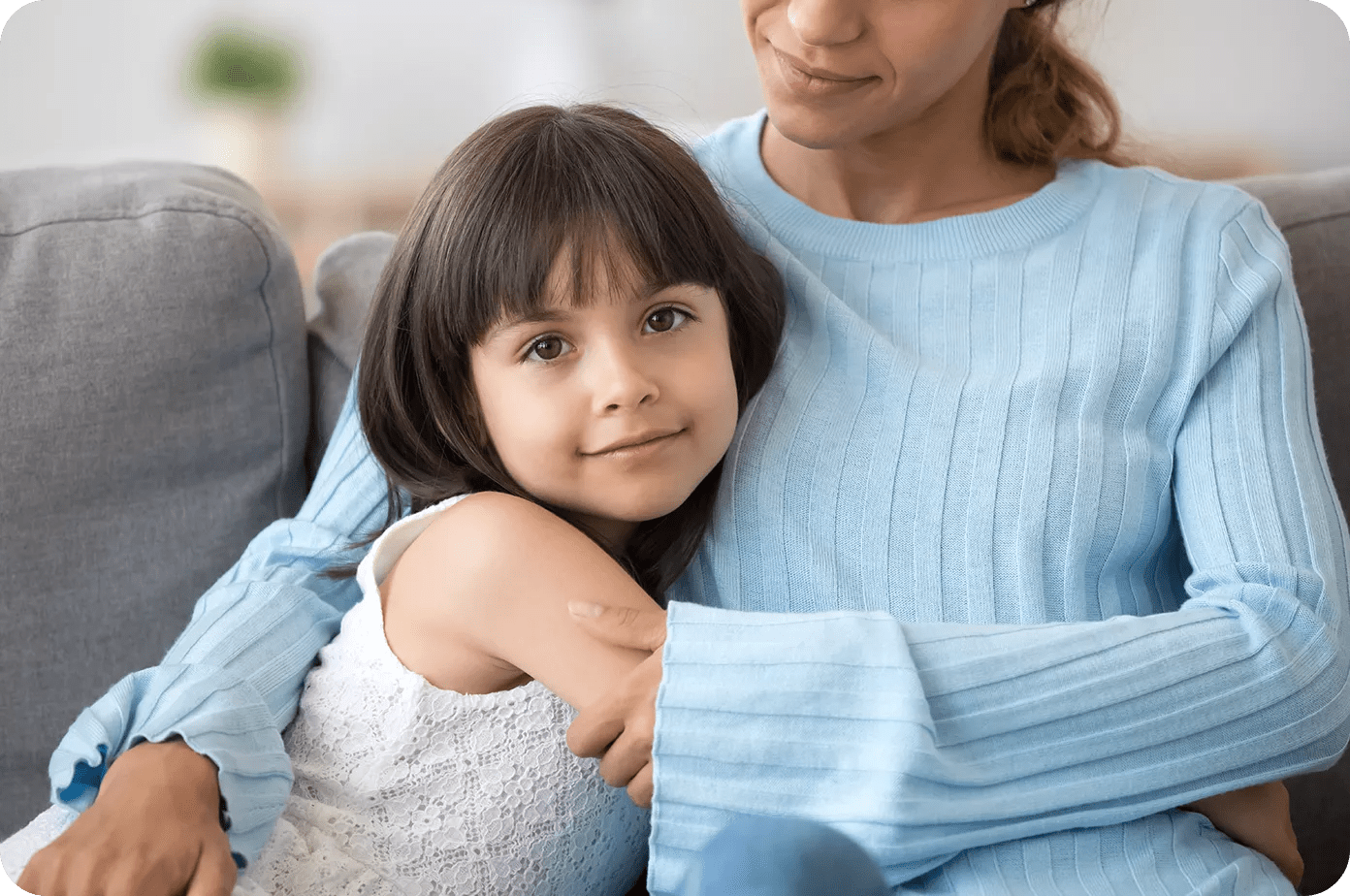 Daughter hugging her mother on the sofa