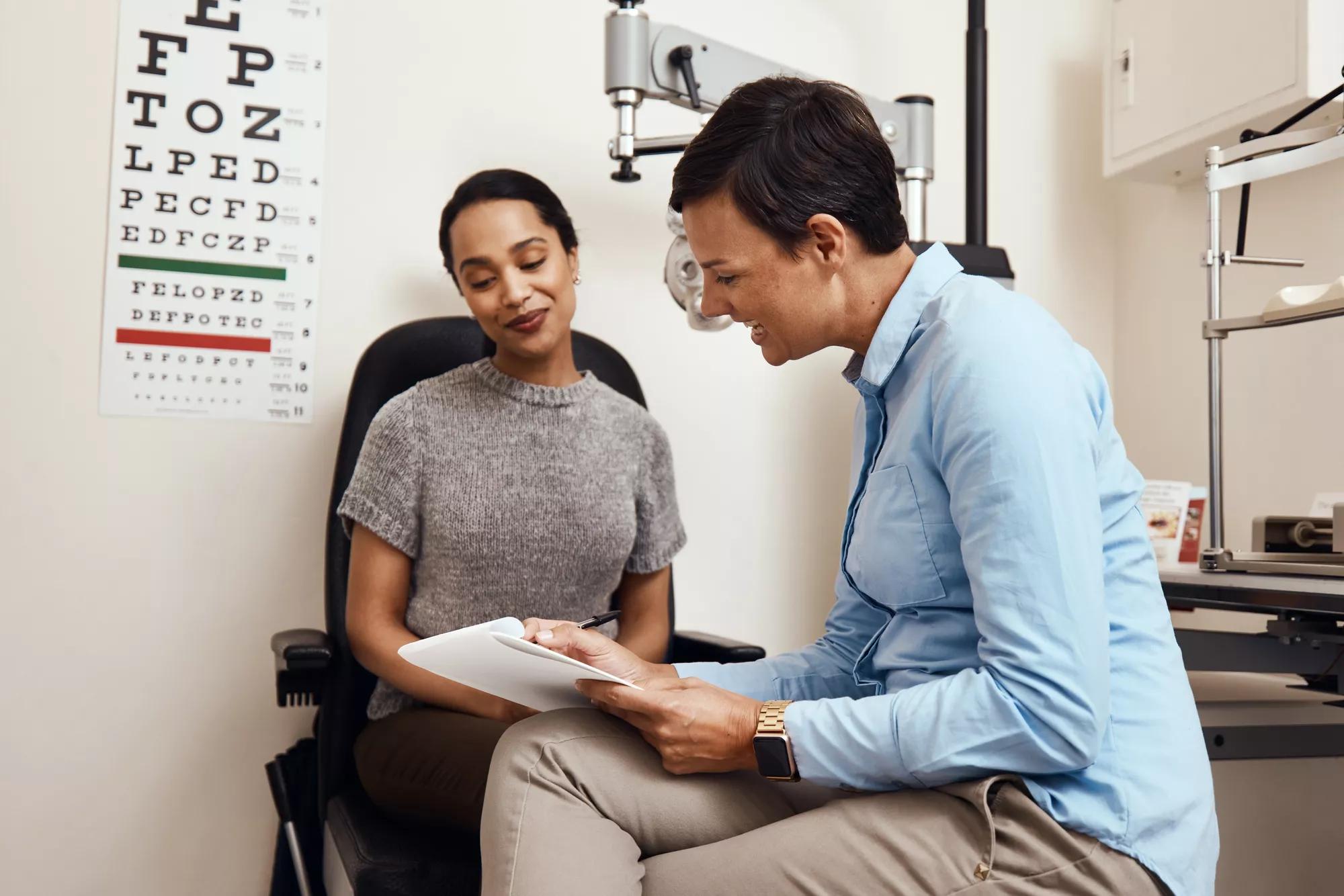 Woman in Eye Exam consulting with eye doctor looking at piece of paper together between them