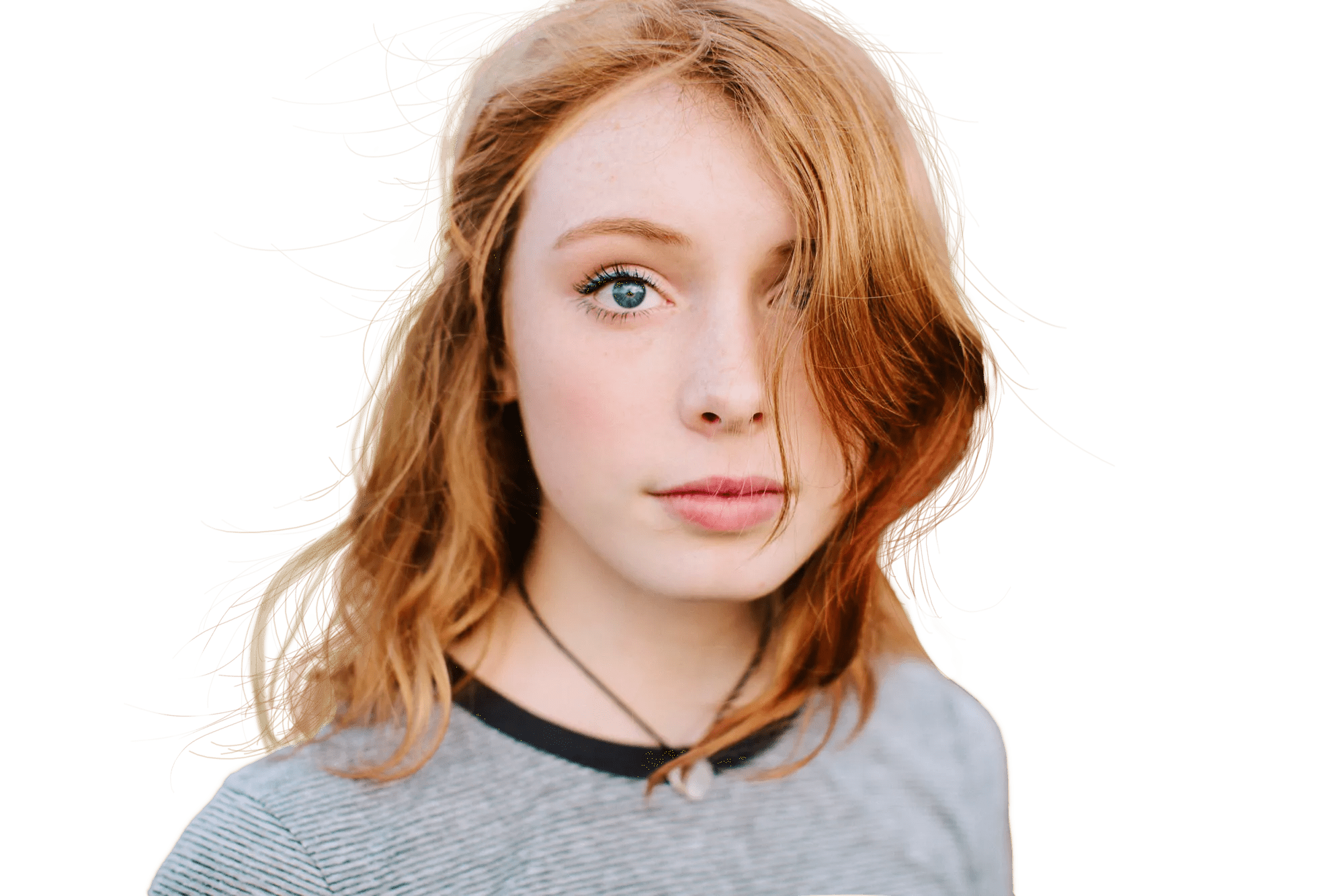 Teen girl with striking red hair with beach waves, wearing a casual gray t-shirt